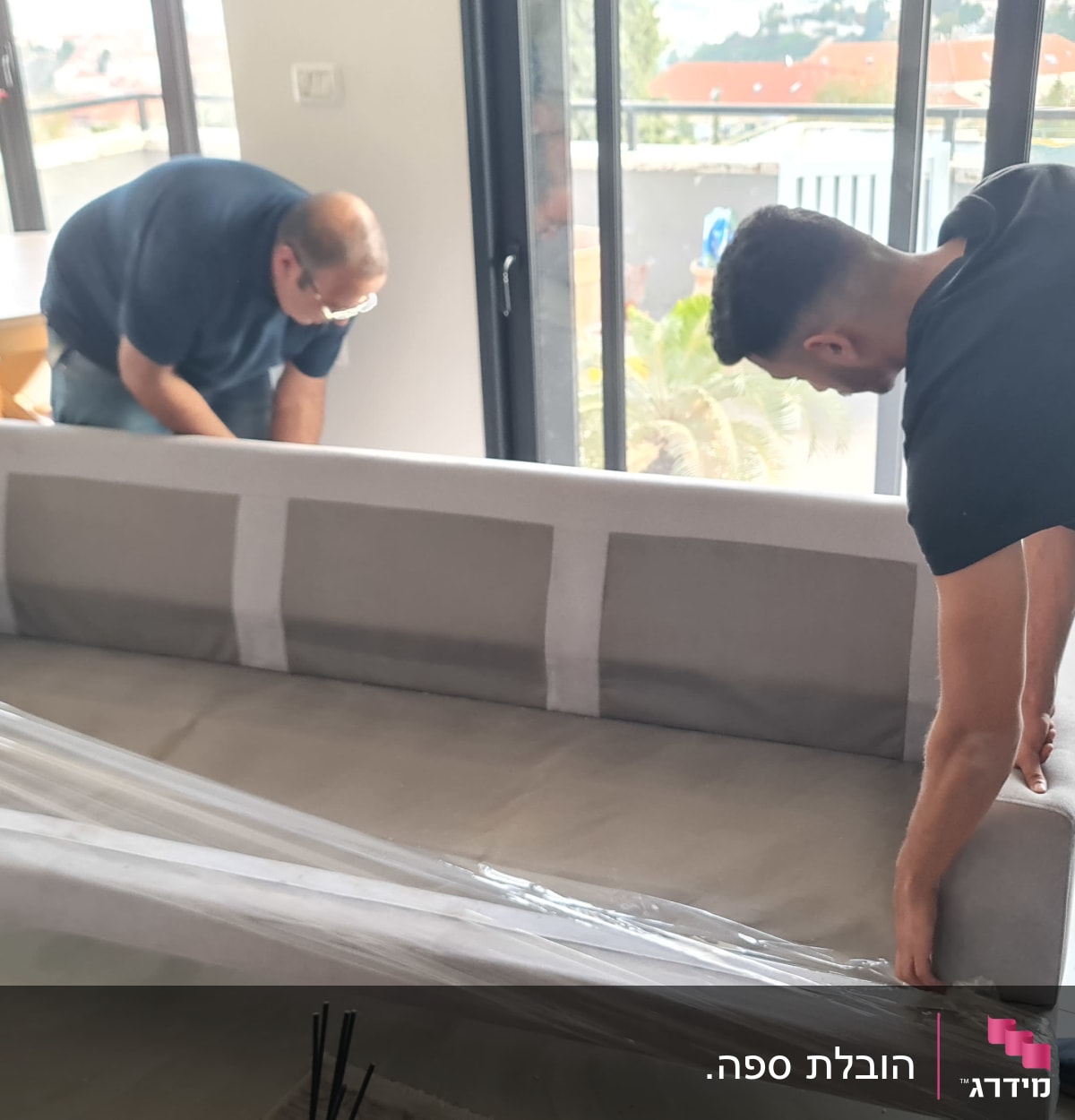 שני אנשים עוטפים ספה בניילון לקראת מעבר דירה